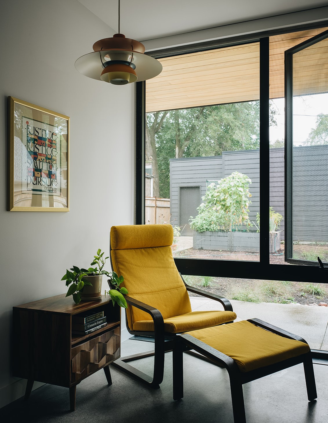 large windows with a view of a small garden with a yellow chair