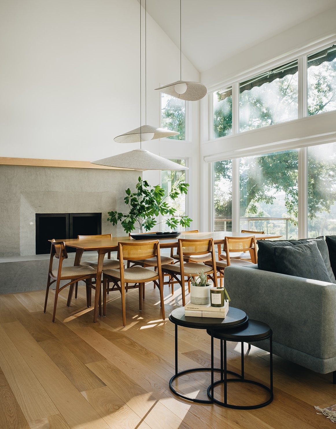 Dining room with hanging lighting, massive windows, and a slab fireplace